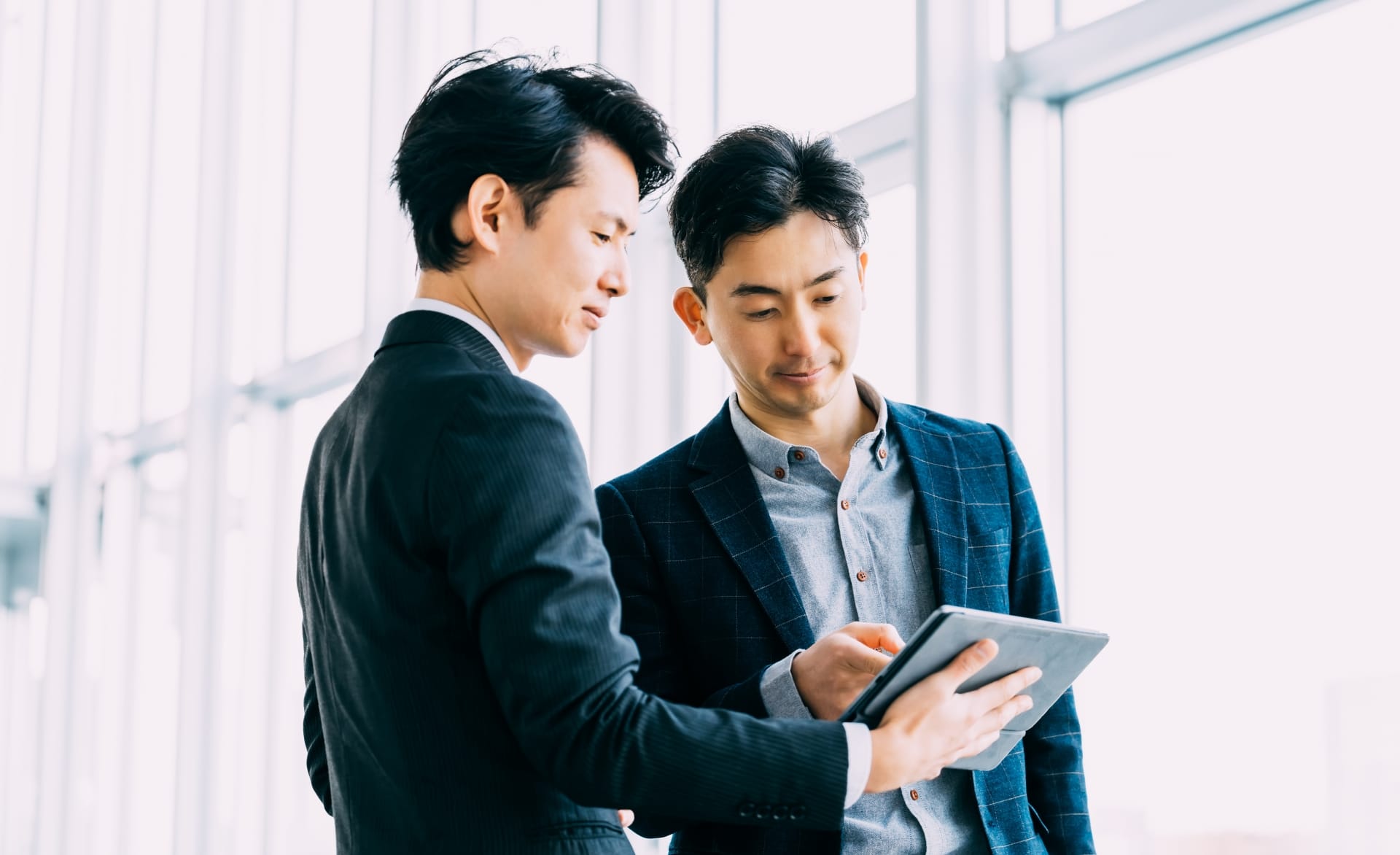 タブレットを見て何かを話し合う男性サラリーマンたち