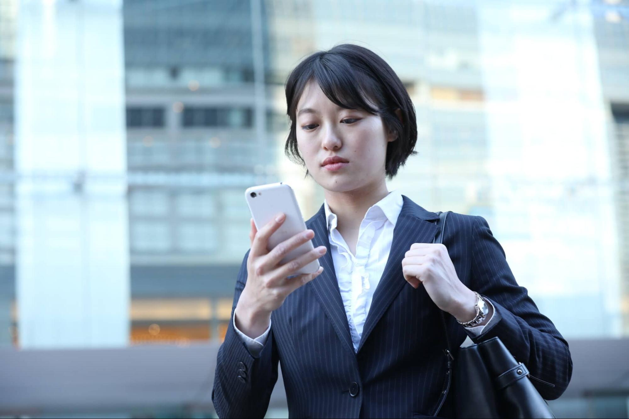 スマホを見ているスーツ姿の女性