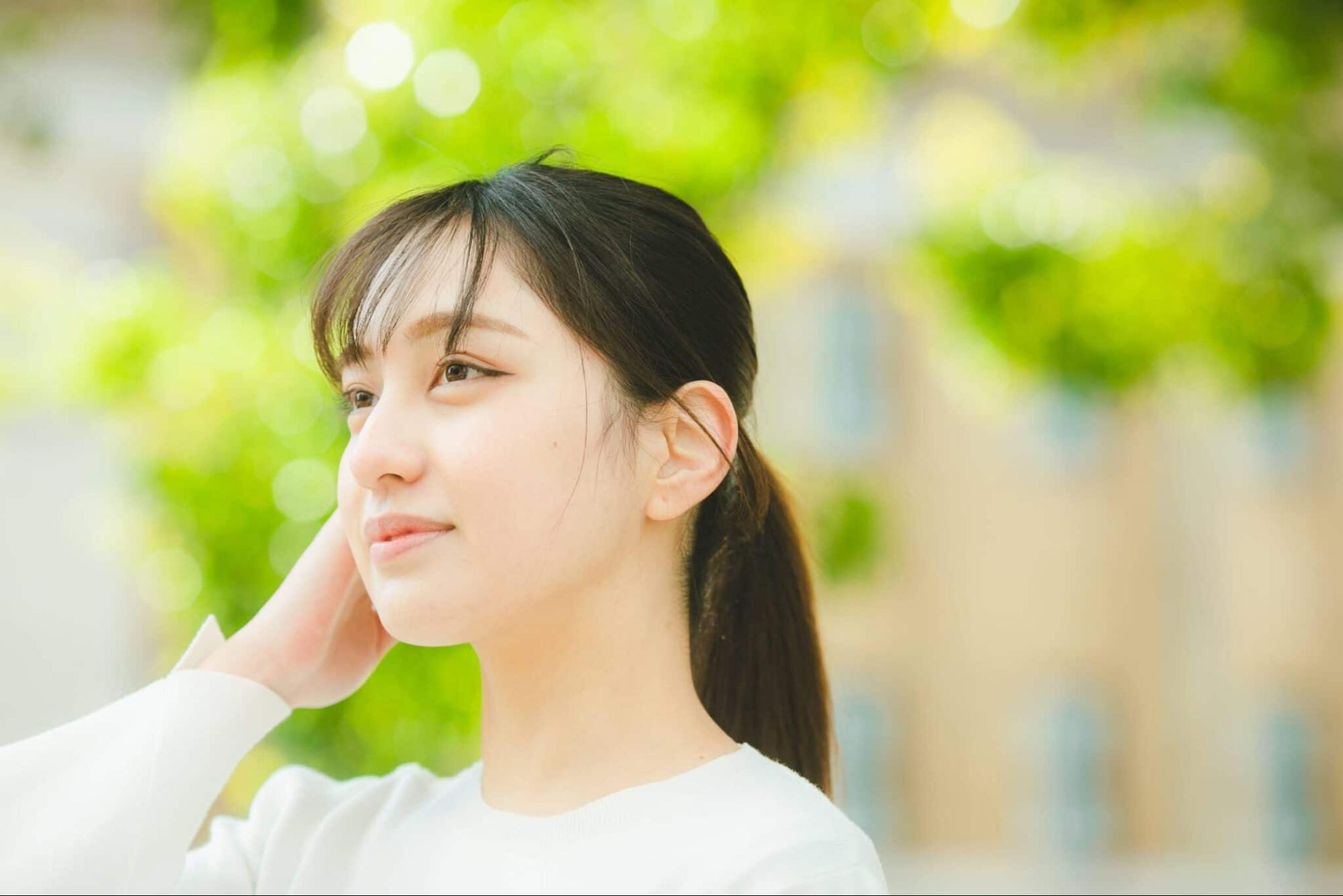 女性の横顔 新緑の背景