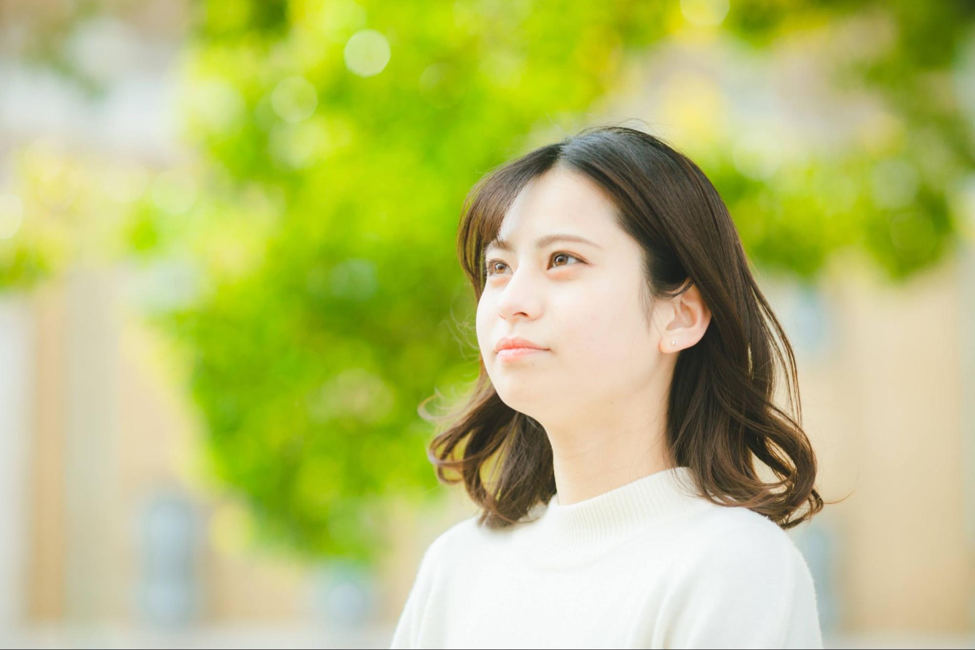 女性の横顔 新緑の背景