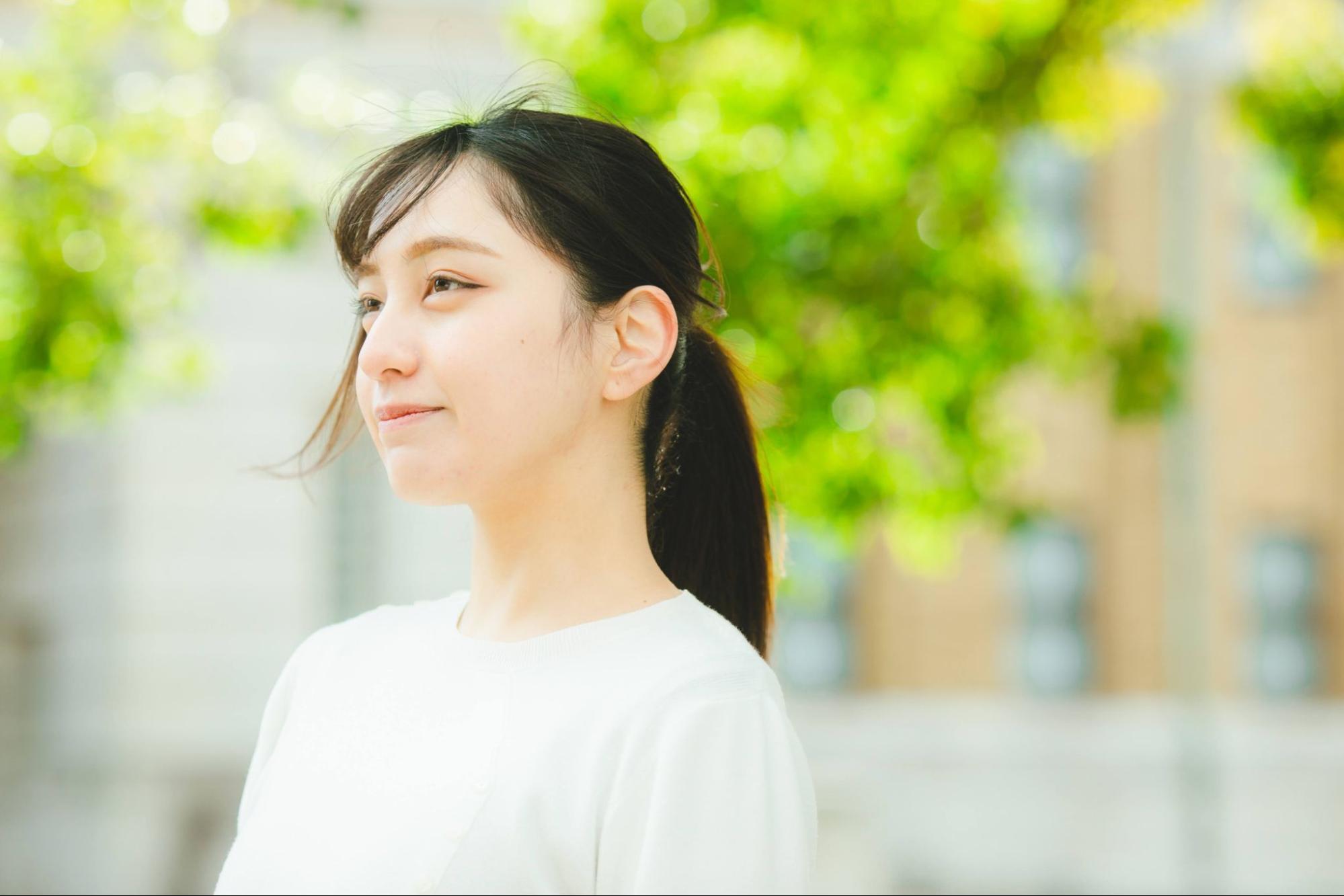 微笑む女性の横顔 新緑の背景