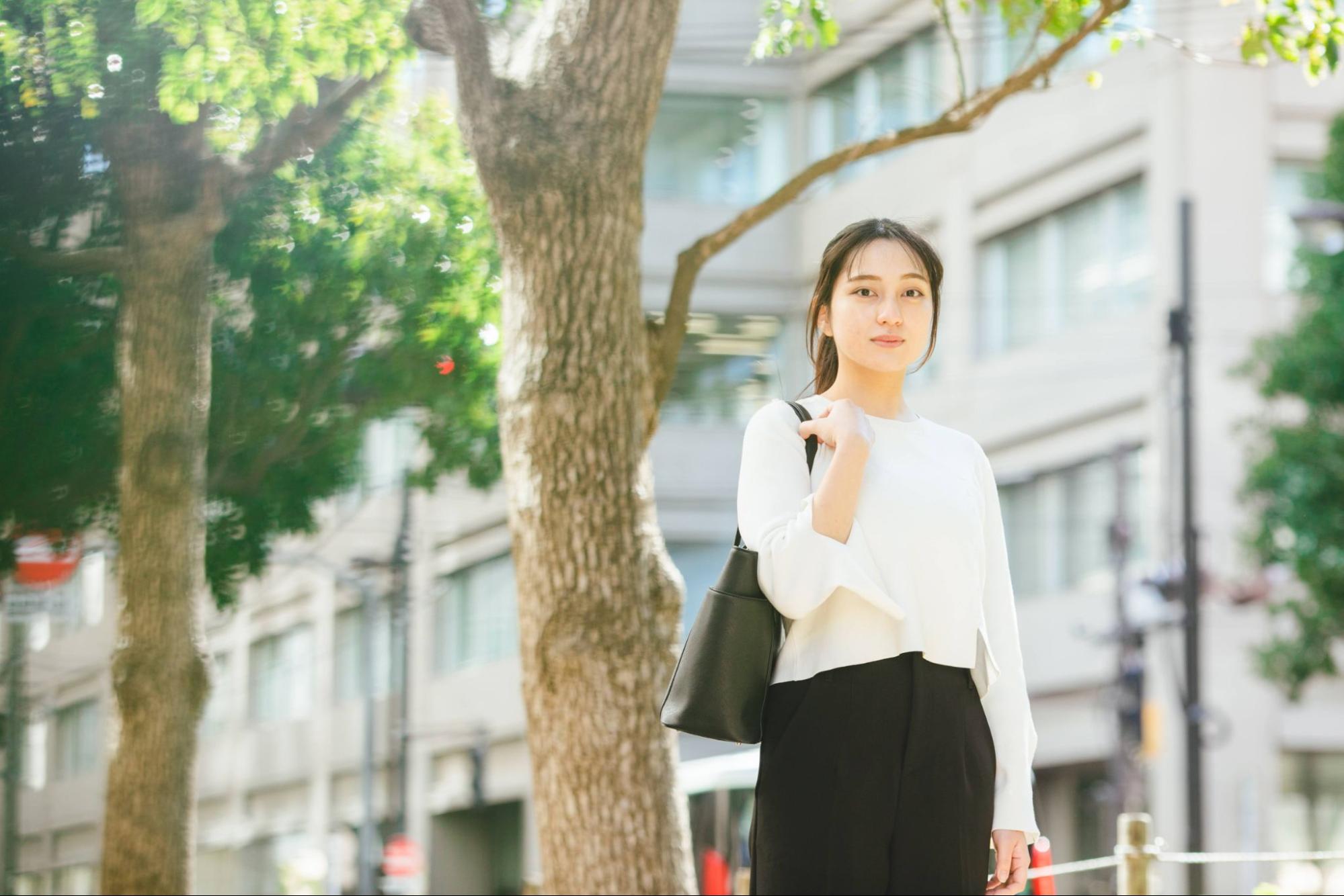 街路樹の下に立つ就活生 女性